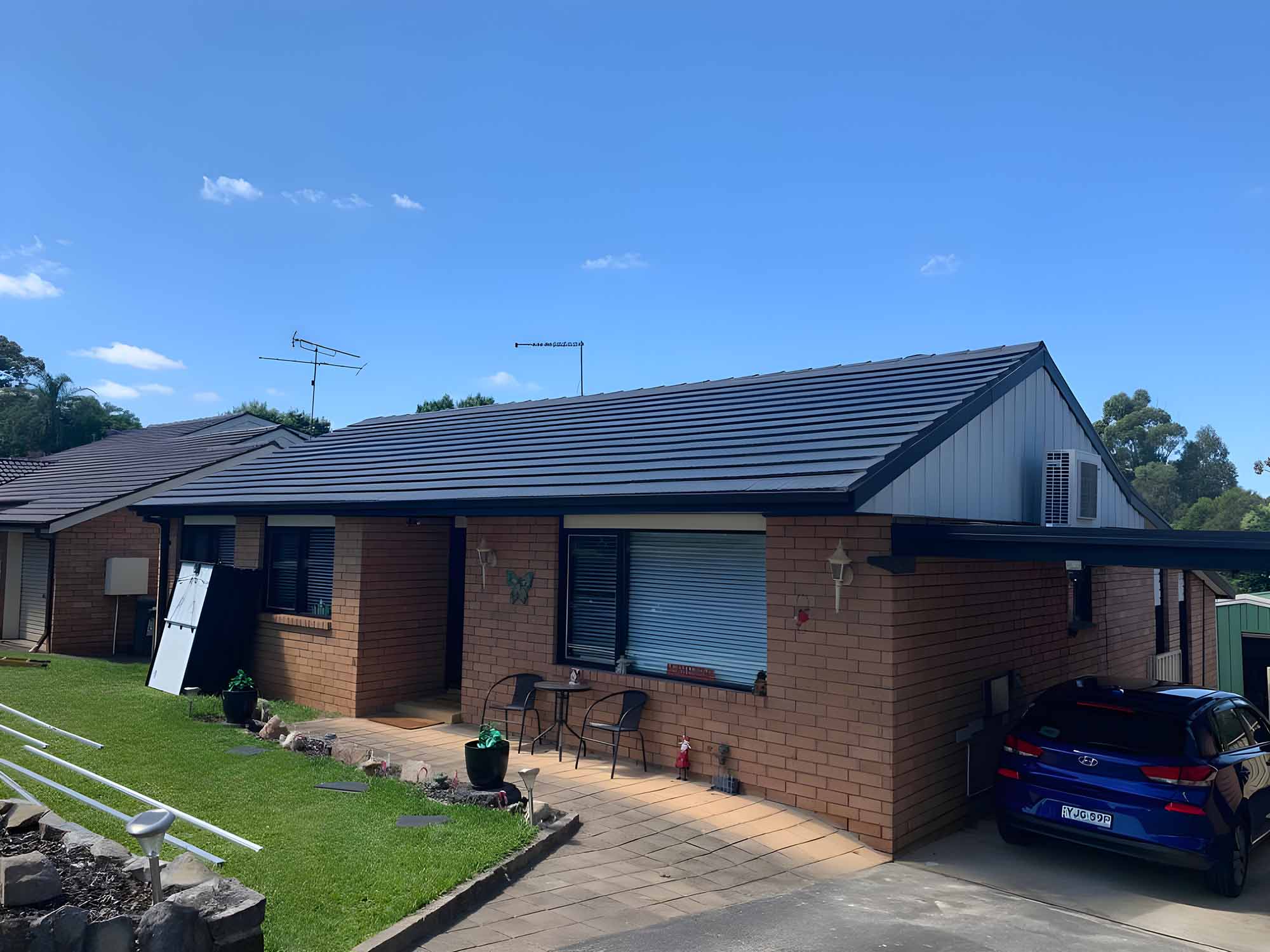about-rs Brick home with a dark charcoal tiled roof and a car in the driveway