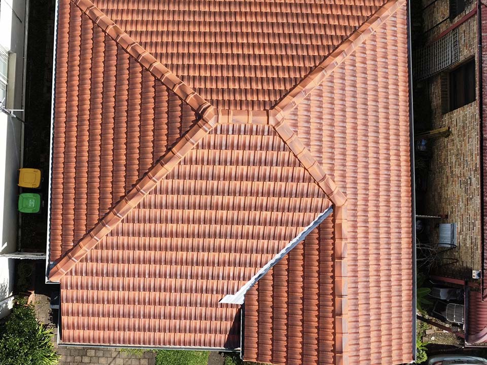 After: aerial view of the same roof with bright terracotta tiles