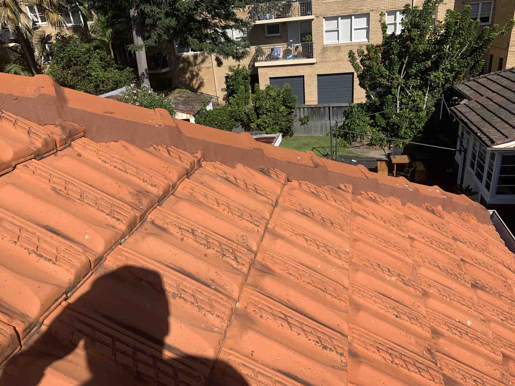 Close-up of terracotta roof tiles with apartments in the background