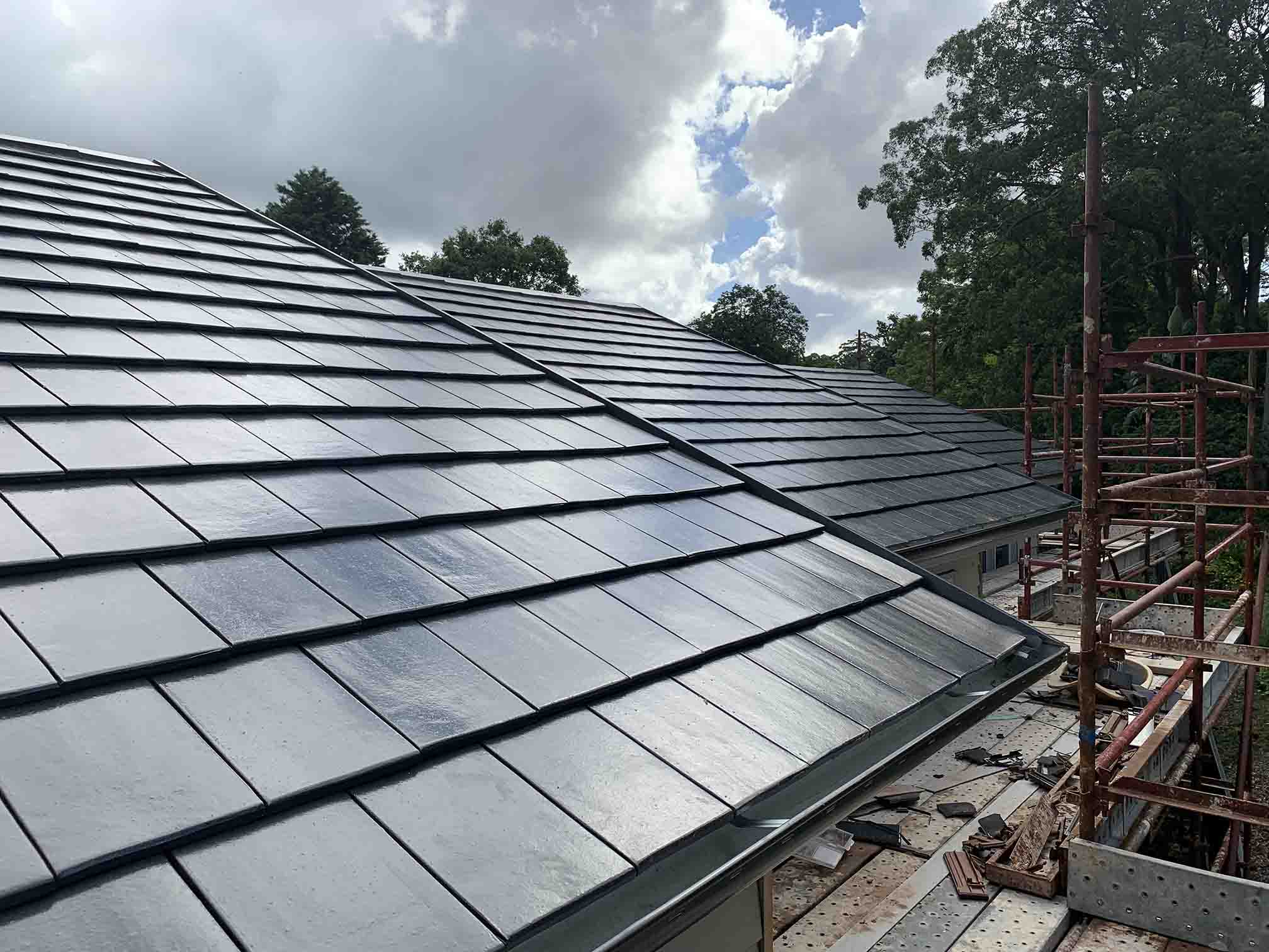 Dark flat roof tiles laid beside scaffolding
