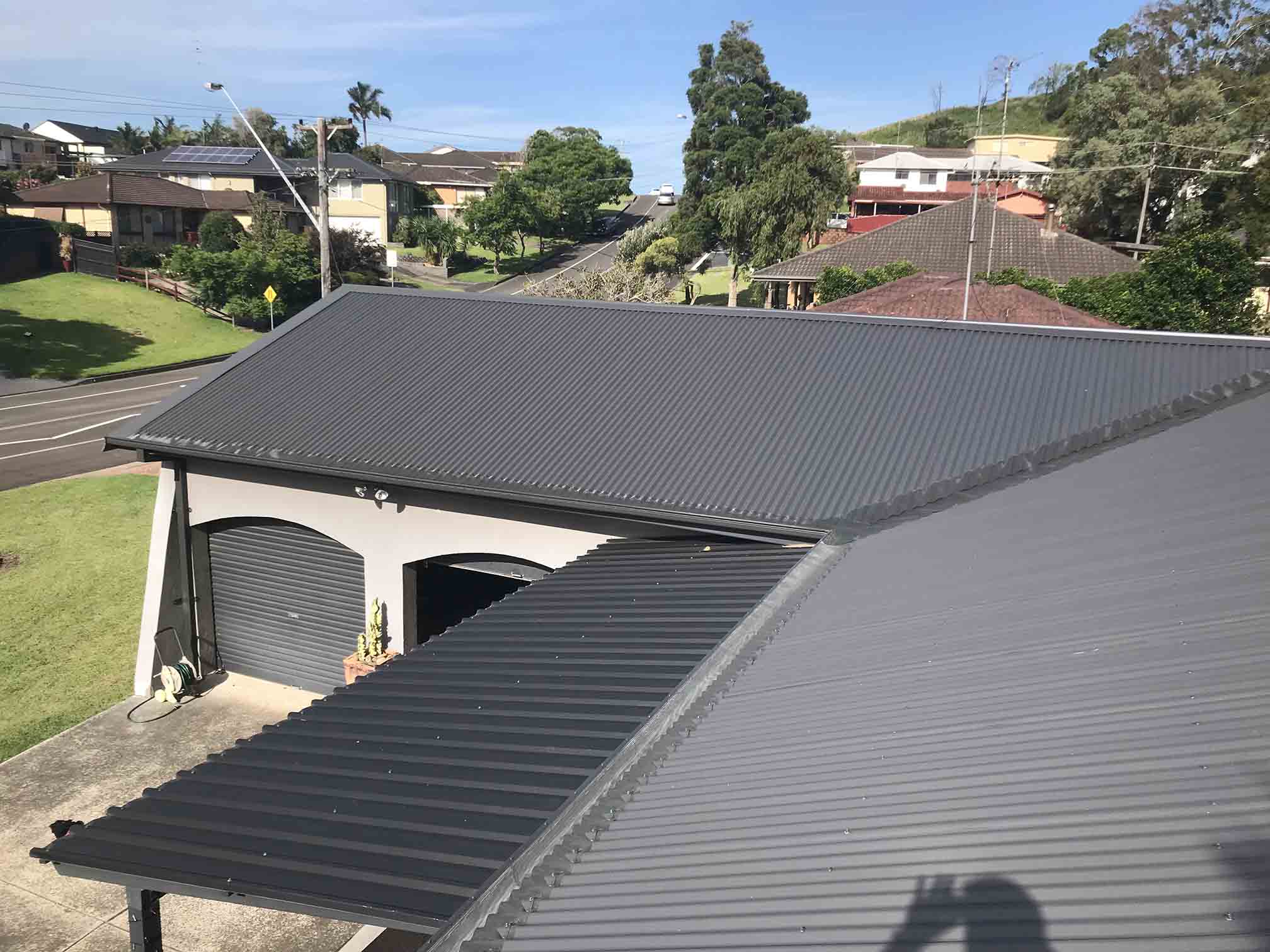 Charcoal corrugated metal roof over a house and double garage