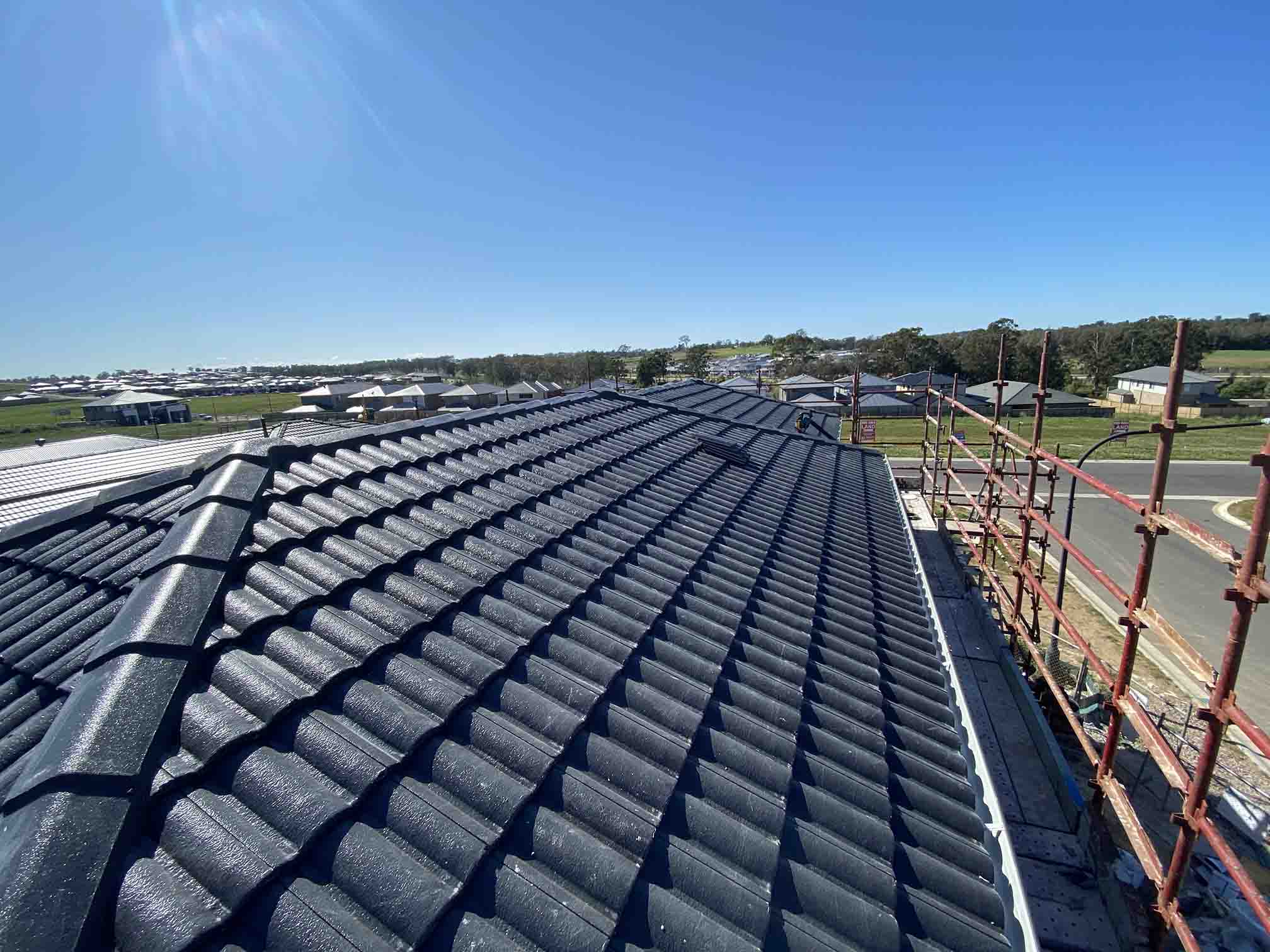 Dark tiled roof on a new house with scaffolding along the edge