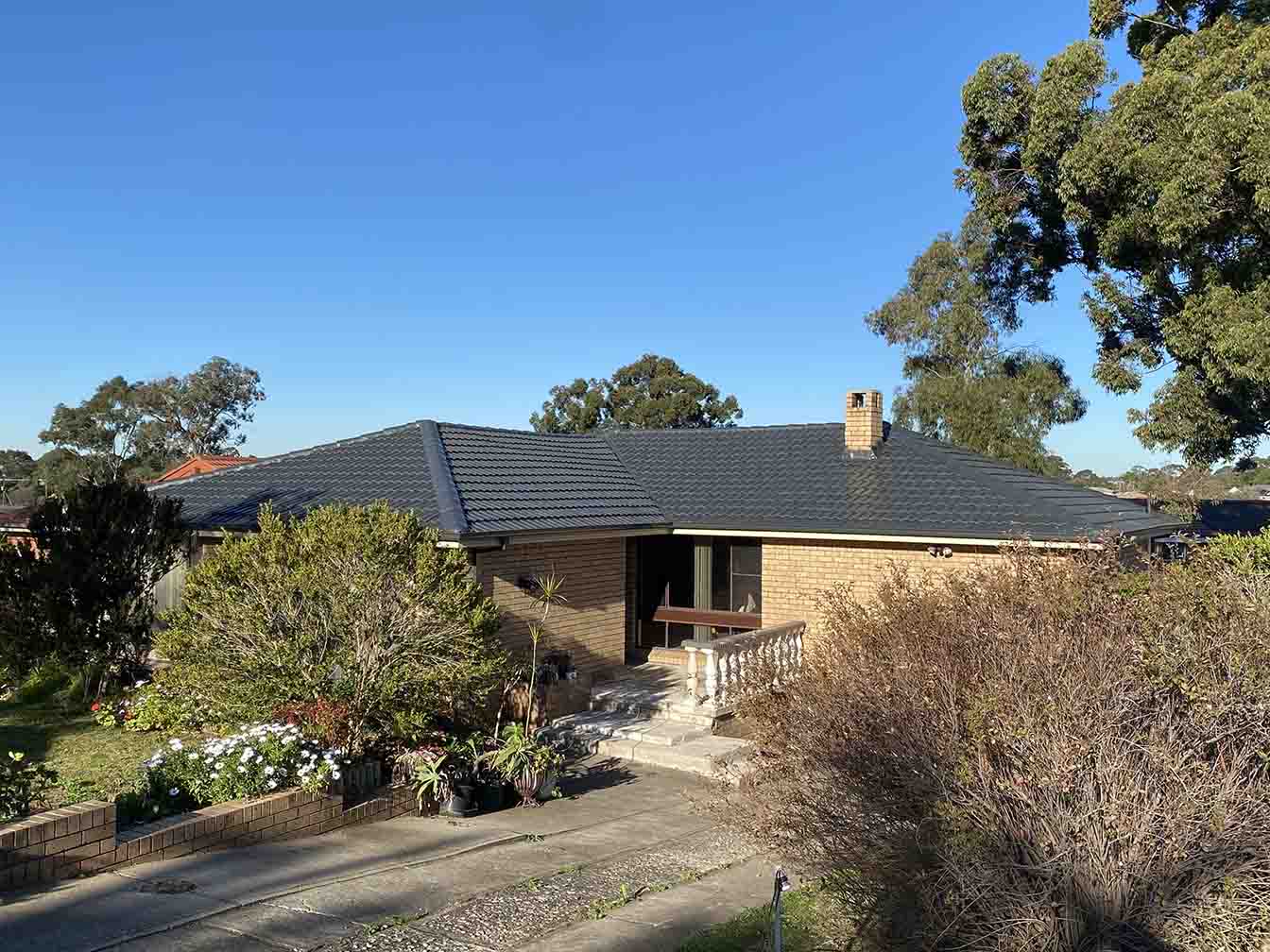 Brick house with a dark tiled roof and a front garden